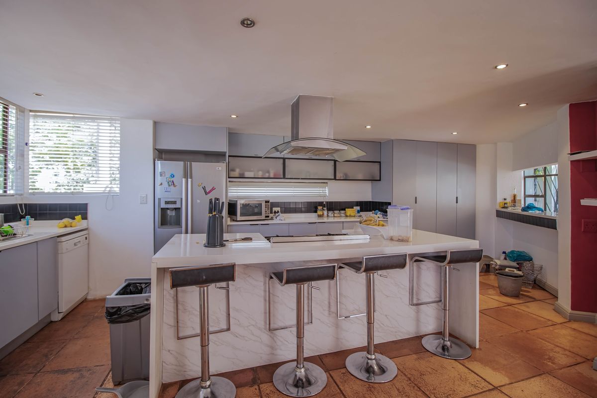 Spacious kitchen featuring a central island with a built-in cooktop, stainless steel extractor fan, ample cabinetry, and integrated appliance space.