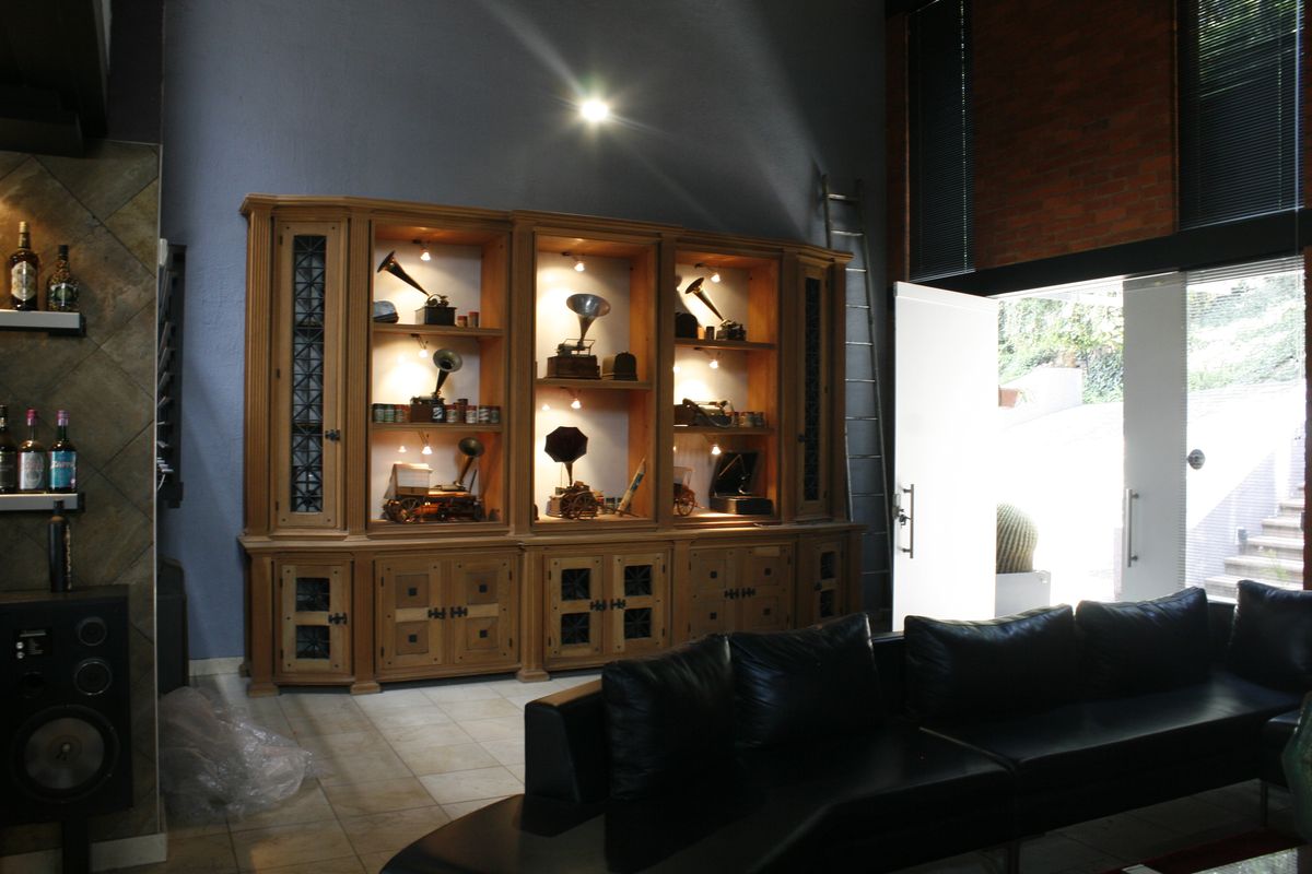 Spacious living area featuring a large built-in wooden display cabinet, tiled flooring, and an exposed brick wall with direct access to the outdoor area.