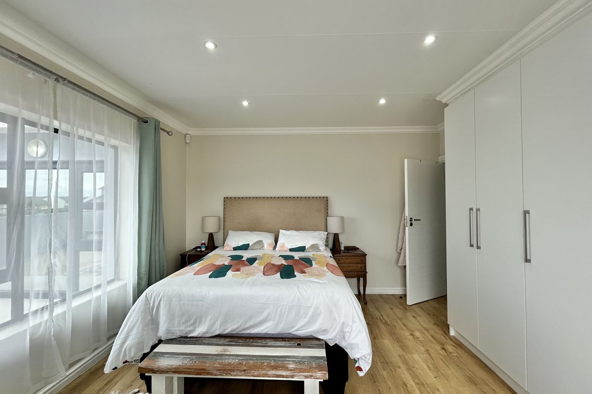 A well-maintained bedroom featuring built-in wardrobes, recessed ceiling lighting, and wood-look flooring, offering a clean and functional living space.