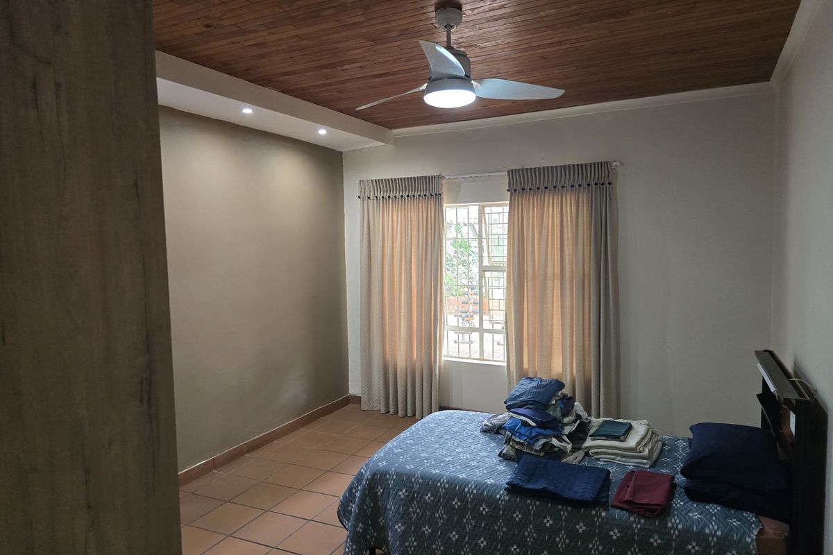 A bedroom featuring a wooden ceiling, tiled flooring, and a ceiling fan, providing a functional and comfortable living space.