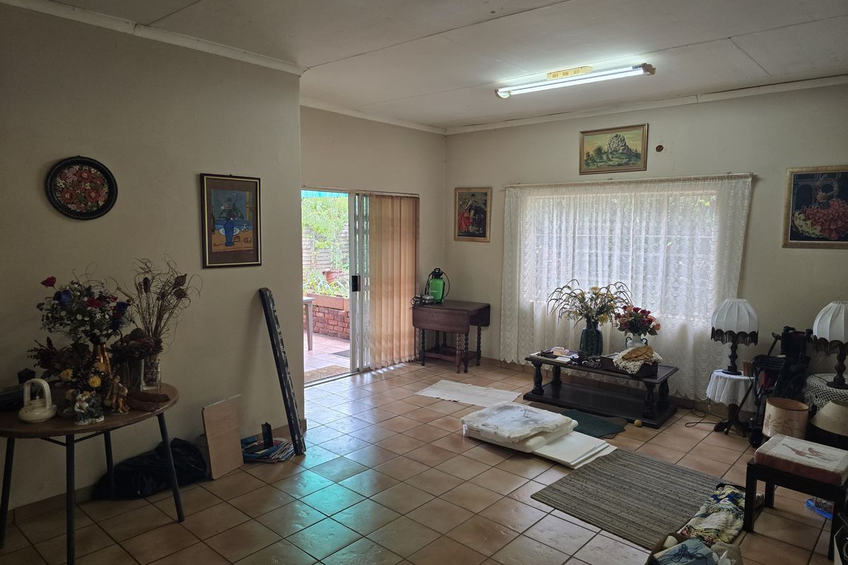 A spacious living area featuring ceramic floor tiles, a large window with curtains, and sliding glass doors providing direct access to the outdoor patio.