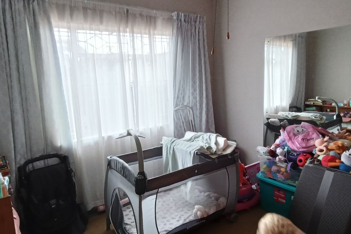 A bedroom featuring a large wall-mounted mirror and a window with curtain tracks.