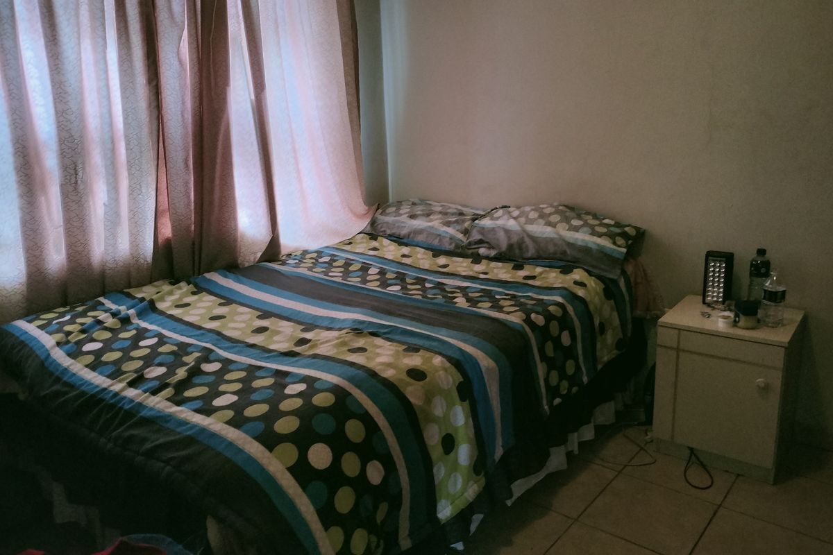 A bedroom featuring tiled flooring and a window with curtains.