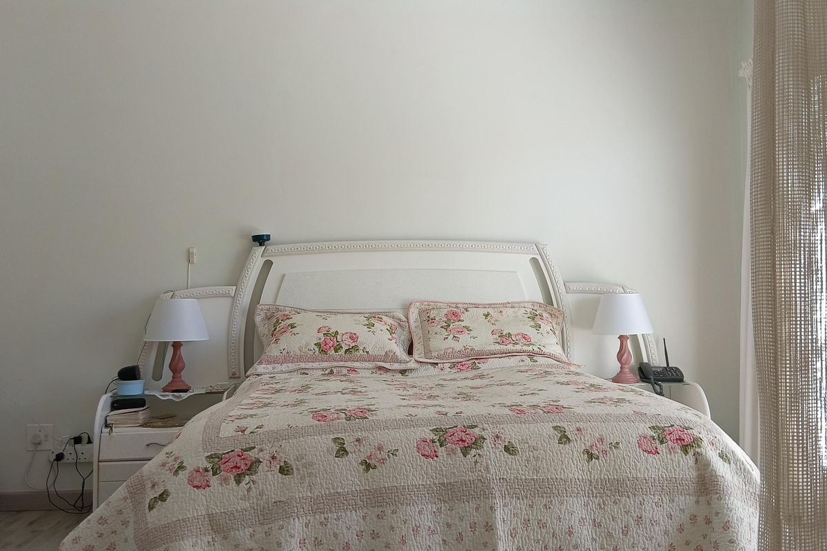 A well-lit bedroom featuring laminate flooring and recessed ceiling lighting, providing a neutral foundation for personal styling.