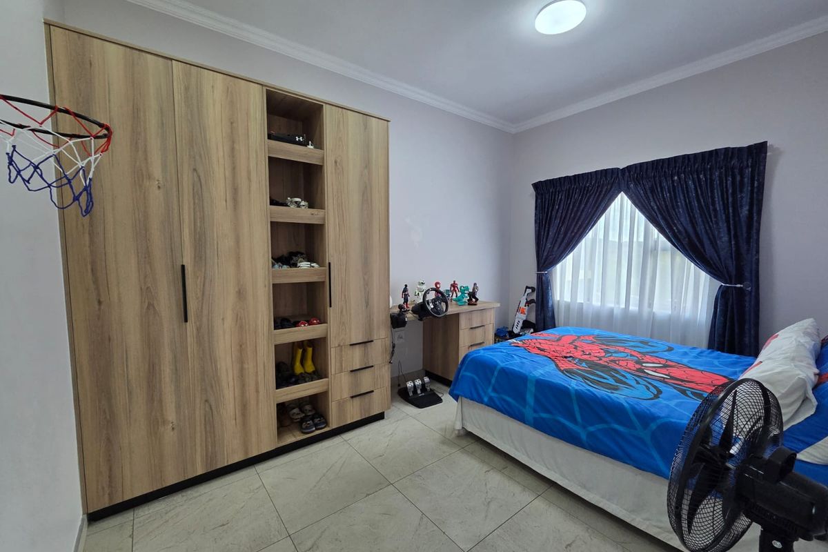 A well-maintained bedroom featuring built-in light wood cabinetry with integrated shelving and tiled flooring.
