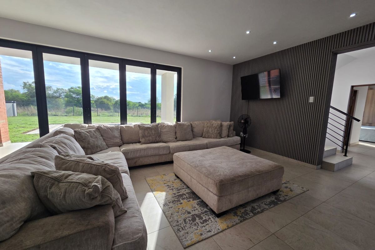 Modern living room featuring large floor-to-ceiling sliding glass doors, tiled flooring, and a contemporary slatted feature wall.