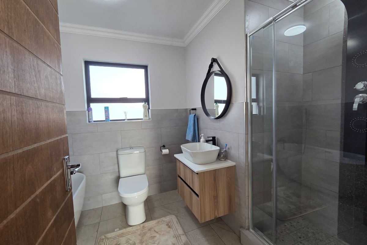 Modern bathroom featuring a floating vanity with vessel sink, glass-enclosed shower, and neutral wall tiling.
