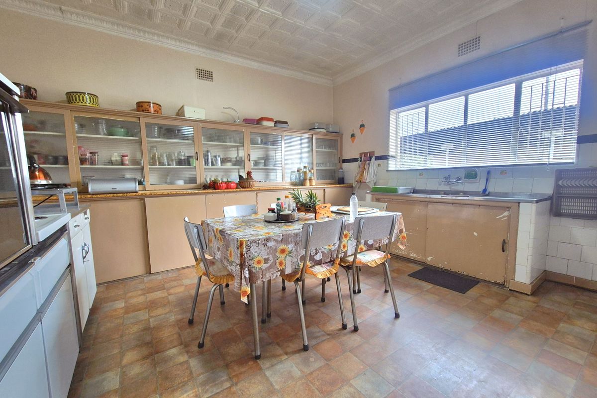 Spacious kitchen featuring extensive built-in cabinetry, a large window for natural light, and a dedicated dining area with original tile flooring.