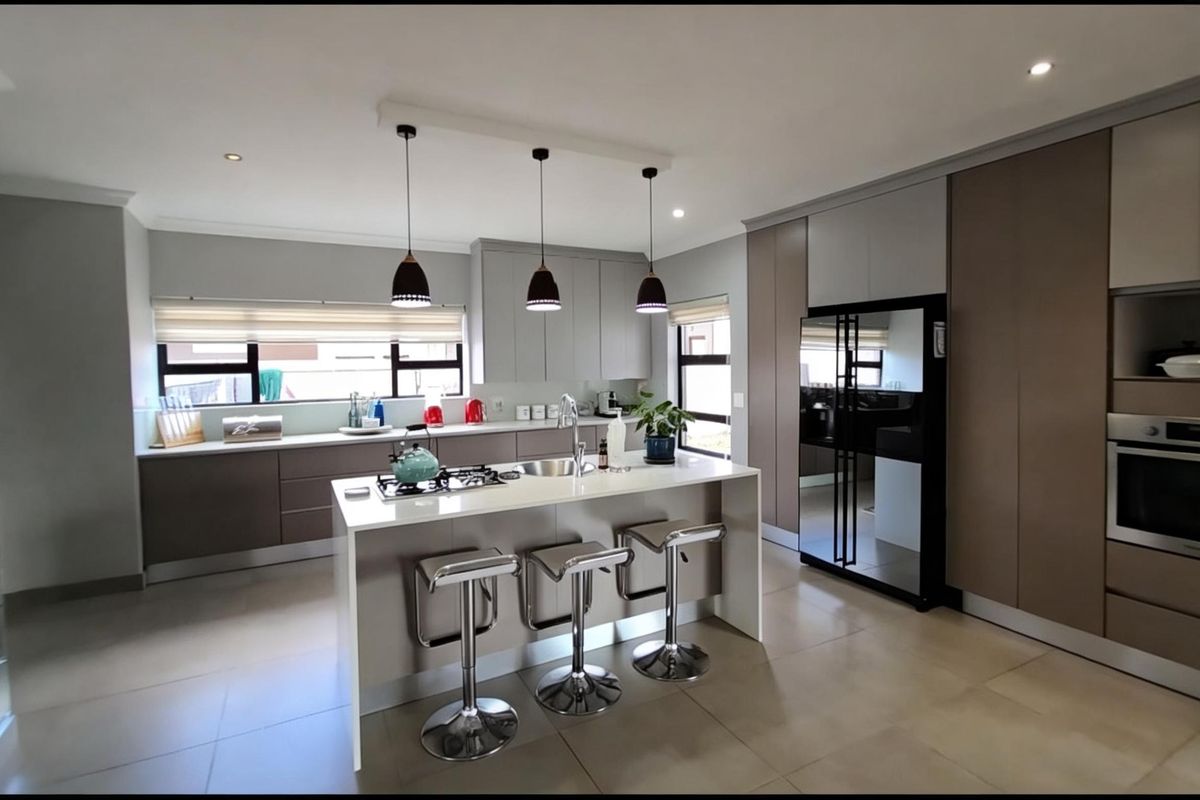 Modern kitchen featuring a central island with a built-in gas hob, sleek cabinetry, integrated oven, and high-quality tiled flooring.