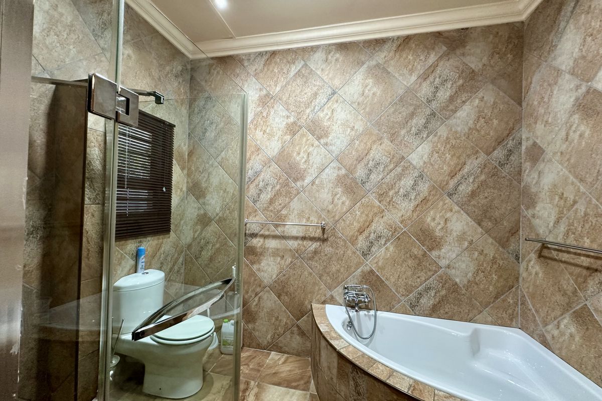 A bathroom featuring a corner bathtub, a glass-enclosed shower, and full-height wall tiling.
