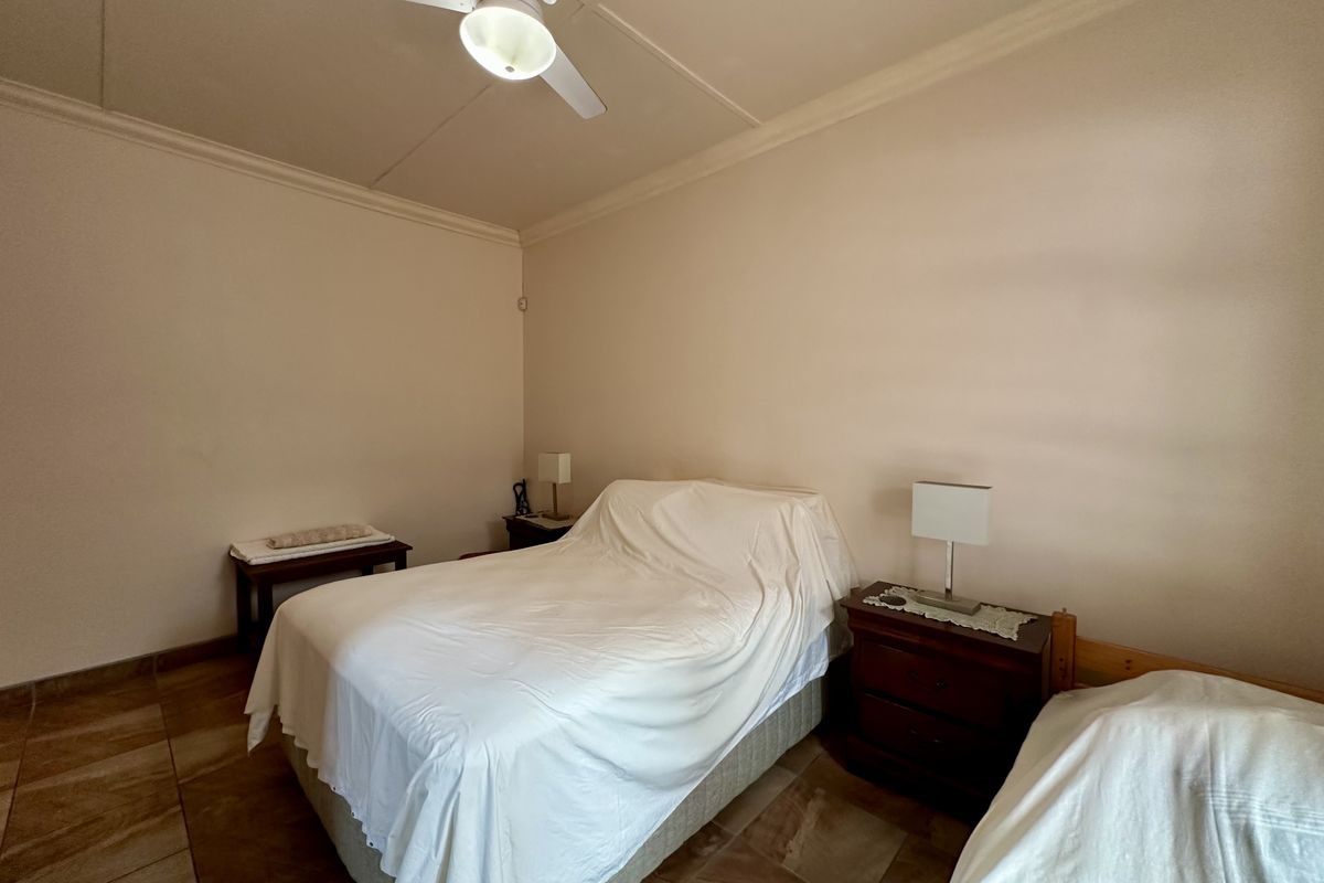 A bedroom featuring tiled flooring, a ceiling fan, and neutral wall finishes.