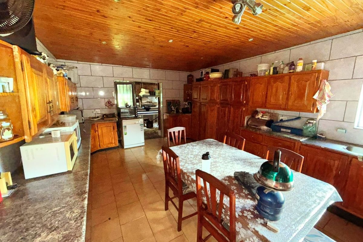 A spacious kitchen featuring extensive wooden cabinetry, tiled walls, and a wood-paneled ceiling, offering a traditional layout with ample storage and workspace.