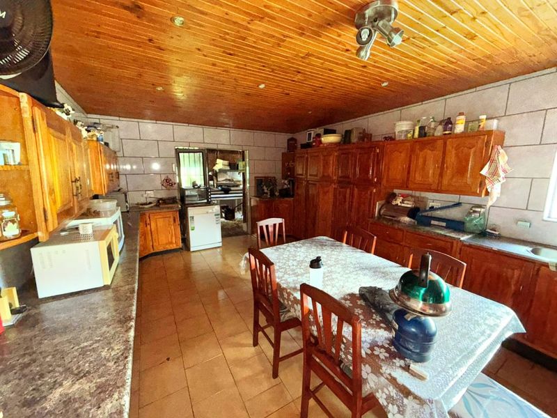 A spacious kitchen featuring extensive wooden cabinetry, tiled walls, and a wood-paneled ceiling, offering a traditional layout with ample storage and workspace.