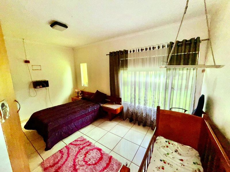 A bedroom featuring tiled flooring, a large window with curtain tracks, and a ceiling-mounted light fixture.