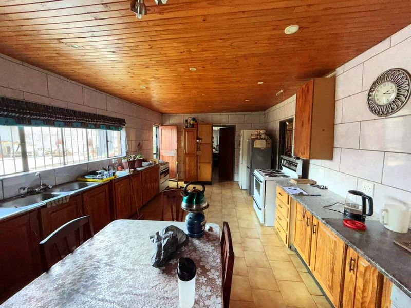 Spacious kitchen featuring wooden cabinetry, tiled countertops, and a warm timber-paneled ceiling, offering a functional layout with ample storage and workspace.