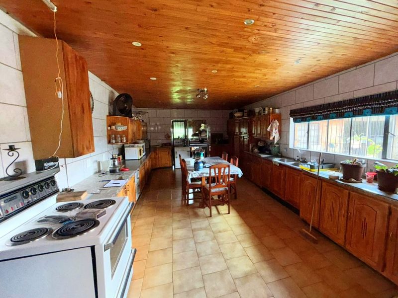 Spacious kitchen featuring extensive wooden cabinetry, tiled flooring, and a timber-clad ceiling, offering a functional layout with ample counter space.