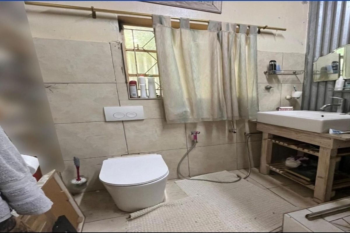 A compact bathroom featuring a wall-mounted toilet, a vessel sink on a wooden vanity, and tiled walls with a window.