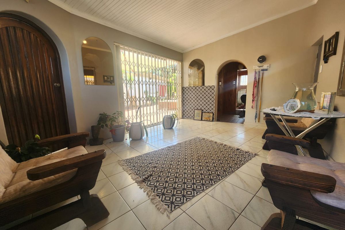 A living area featuring tiled flooring, arched doorways, a tongue-and-groove ceiling, and a security gate leading to the exterior.