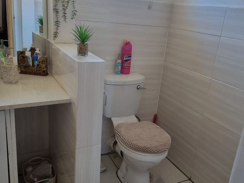 A functional bathroom featuring a tiled vanity area with a built-in basin and a separate toilet section with neutral wall and floor tiles.