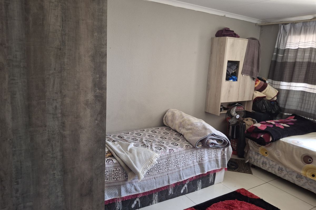 A bedroom featuring tiled flooring and a built-in wall cabinet, providing functional storage space within the room.
