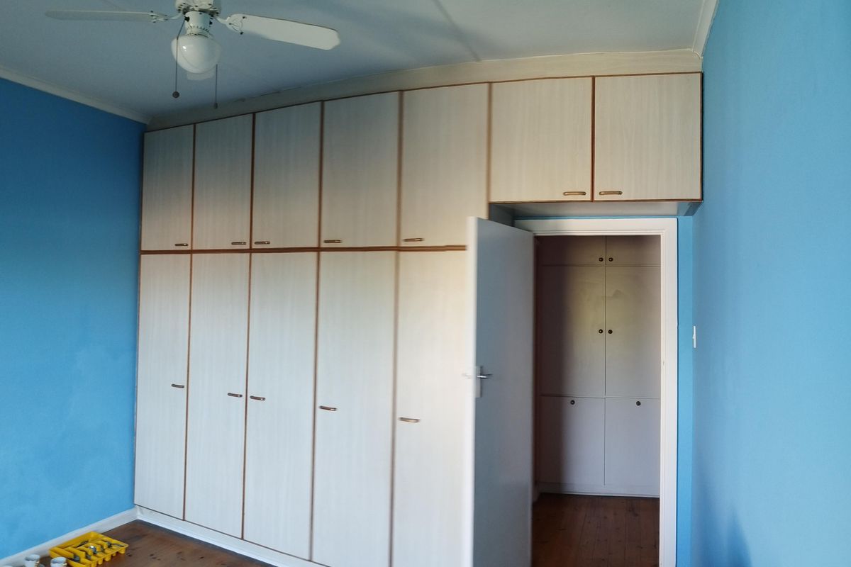 Bedroom featuring extensive built-in floor-to-ceiling cabinetry, wooden flooring, and a ceiling fan.