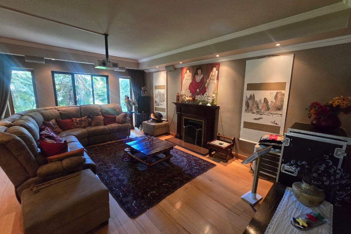 Spacious living room featuring hardwood flooring, crown molding, recessed lighting, and a central fireplace, currently set up as a home cinema area.