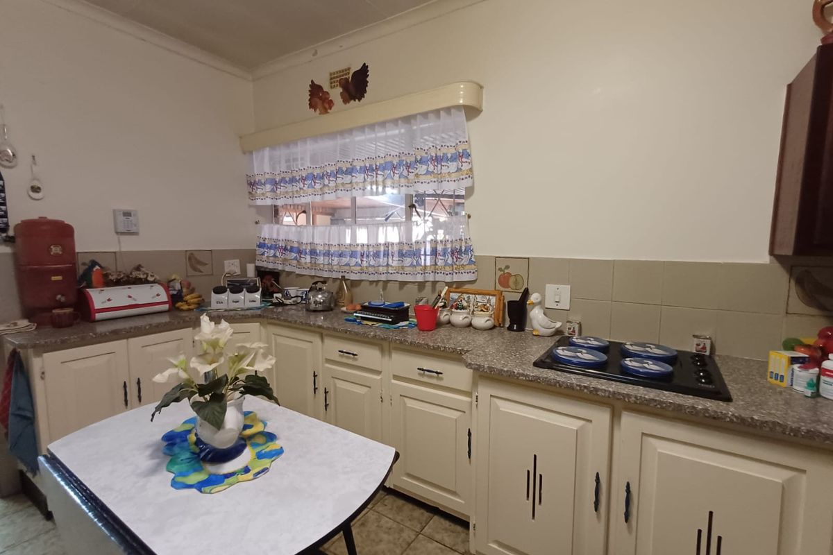 A functional kitchen featuring traditional cabinetry, tiled backsplash, and a built-in electric hob, offering a classic layout with ample counter space.