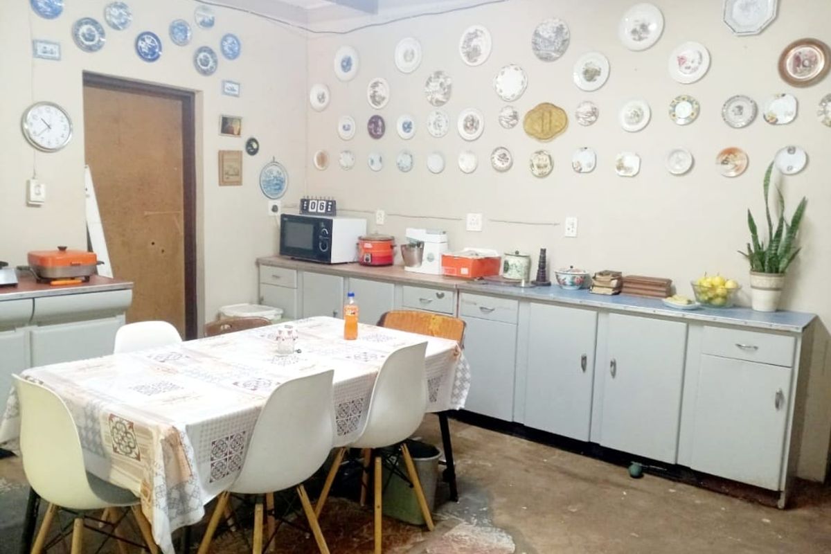 A rustic kitchen and dining area featuring dated cabinetry, exposed electrical wiring, and a concrete floor, offering a functional space with potential for renovation.