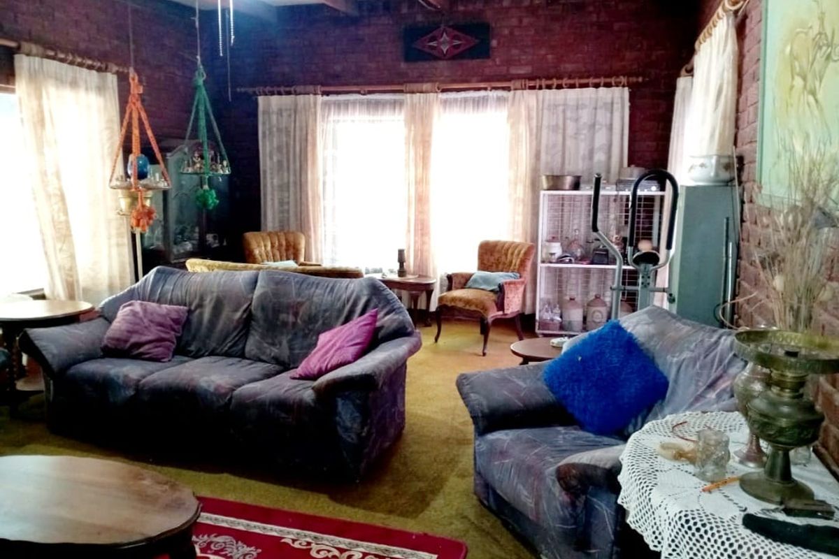 Spacious living room featuring exposed brick walls, timber ceiling beams, and large windows allowing for natural light.