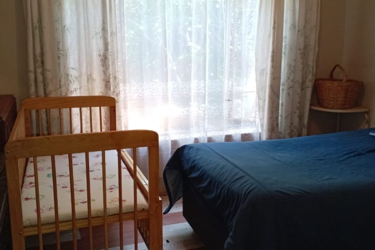 A bedroom featuring patterned vinyl flooring and a large window with curtains, providing natural light to the space.