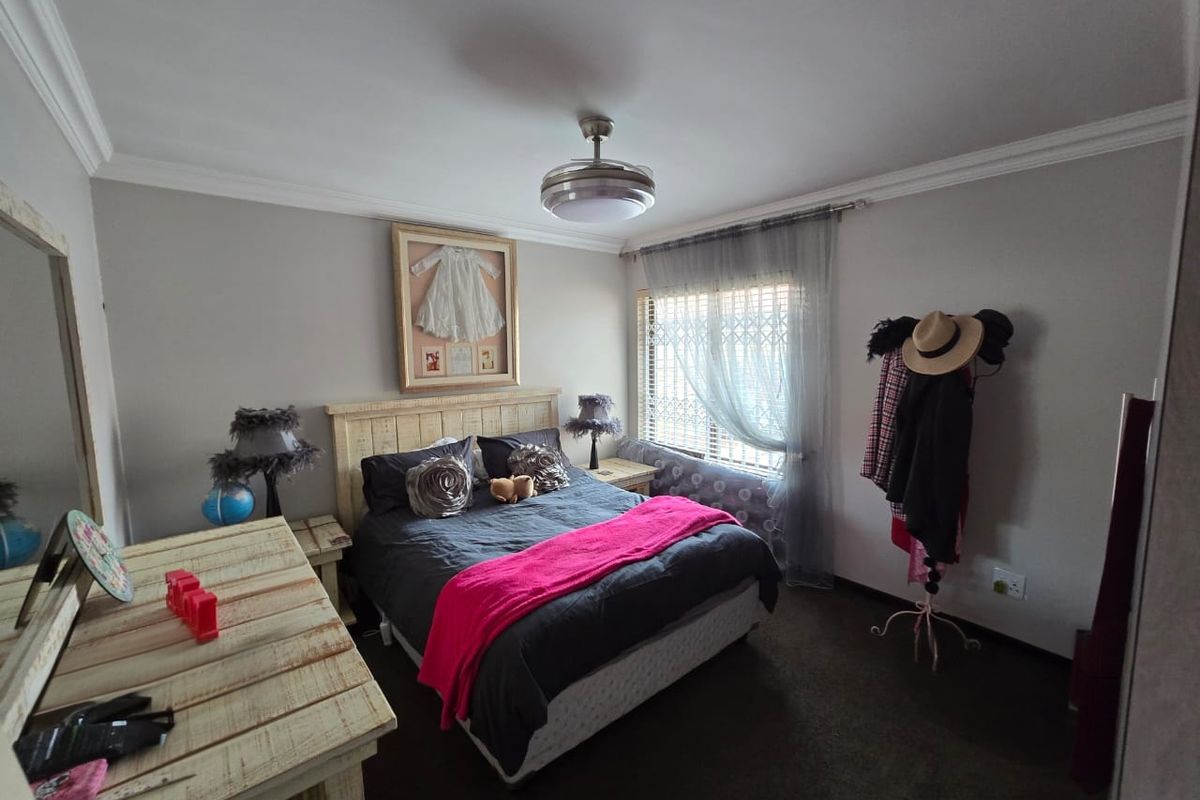 A well-maintained bedroom featuring crown molding, a ceiling fan, and security bars on the window.