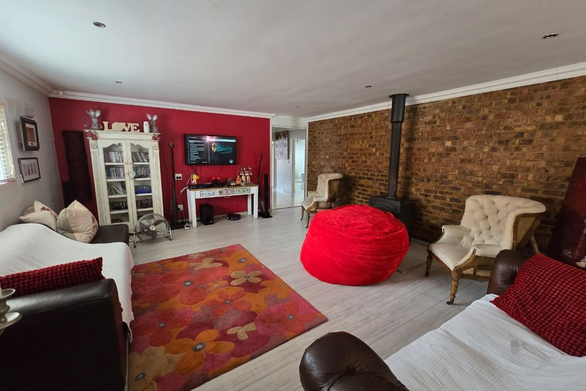 Spacious living room featuring a prominent exposed brick feature wall, a freestanding wood-burning fireplace, and light-toned laminate flooring.
