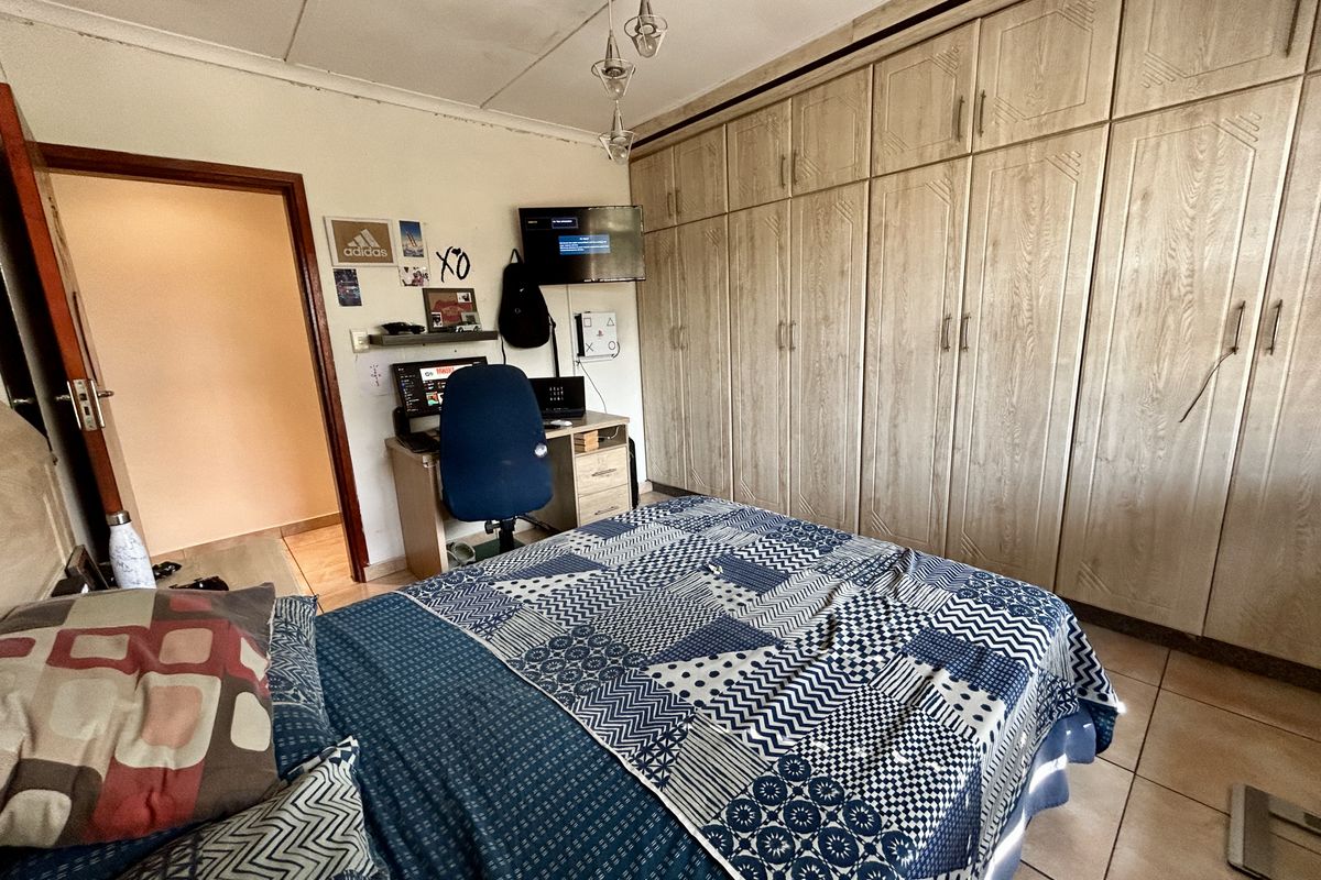 A bedroom featuring extensive built-in wooden cabinetry, tiled flooring, and a central light fixture.
