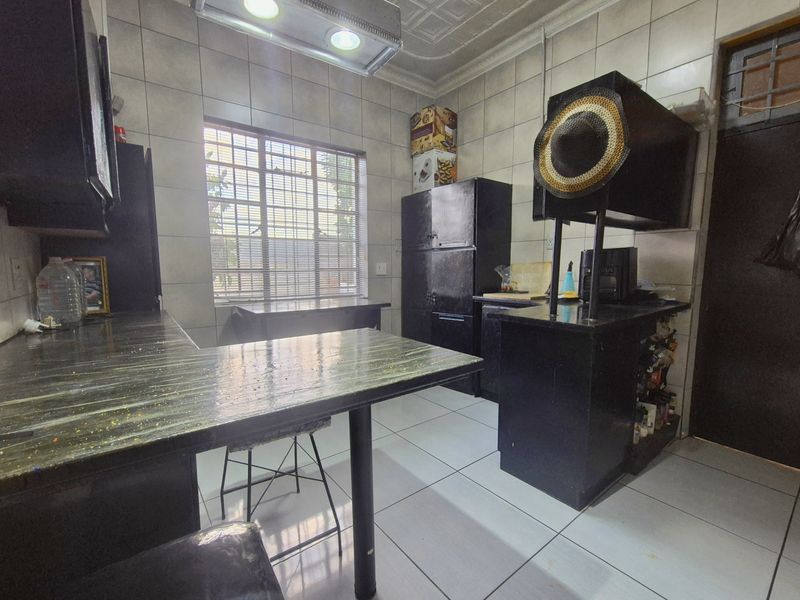 A functional kitchen featuring tiled walls and flooring, built-in cabinetry, and laminate countertops, offering a practical layout with potential for modern updates.