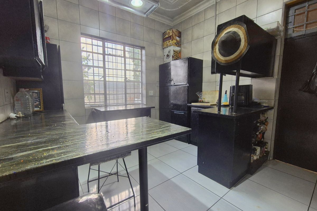 A functional kitchen featuring tiled walls and flooring, built-in cabinetry, and laminate countertops, offering a practical layout with potential for modern updates.
