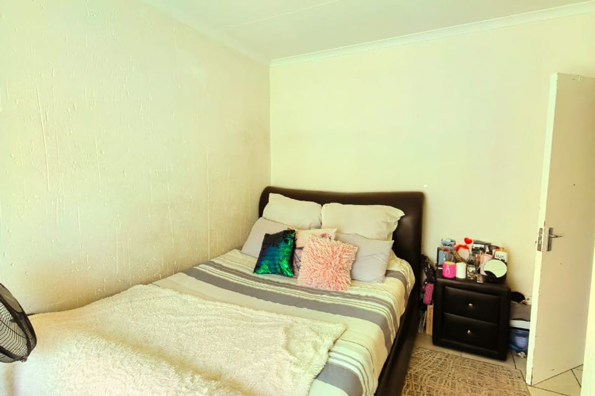 A standard bedroom featuring tiled flooring, a central ceiling light fixture, and textured wall finishes.