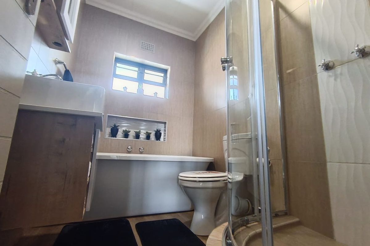 Modern bathroom featuring a glass-enclosed corner shower, a built-in bathtub, and a vanity unit with integrated basin.