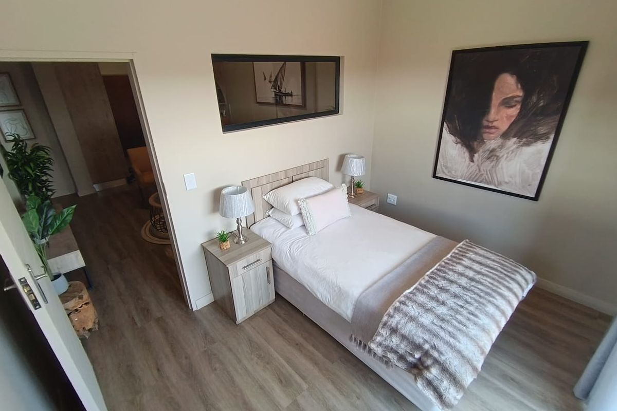 A well-maintained bedroom featuring modern wood-look laminate flooring and a high-level horizontal window, providing a bright and comfortable living space.