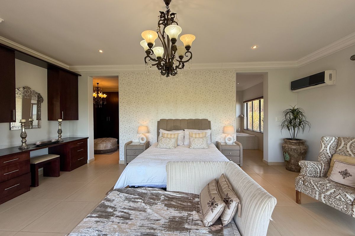 Spacious primary bedroom featuring built-in cabinetry, a vanity area, tiled flooring, and an en-suite bathroom access.