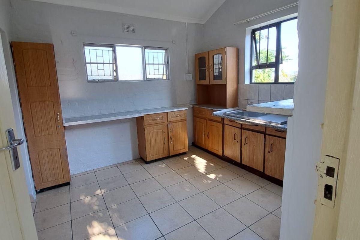 A functional kitchen featuring wooden cabinetry, tiled flooring, and ample counter space, offering a practical layout ready for potential updates.