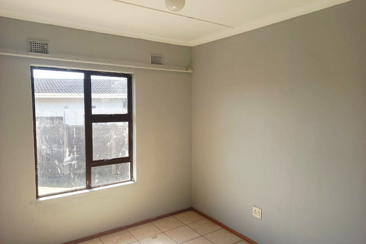 A vacant bedroom featuring tiled flooring, a single window, and neutral wall paint, offering a blank canvas for personalization.