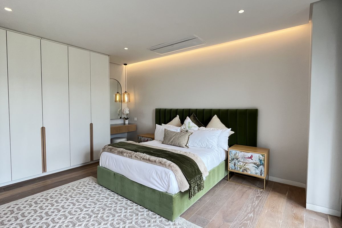 A modern, well-appointed bedroom featuring built-in floor-to-ceiling wardrobes, recessed ceiling lighting, and integrated air conditioning.