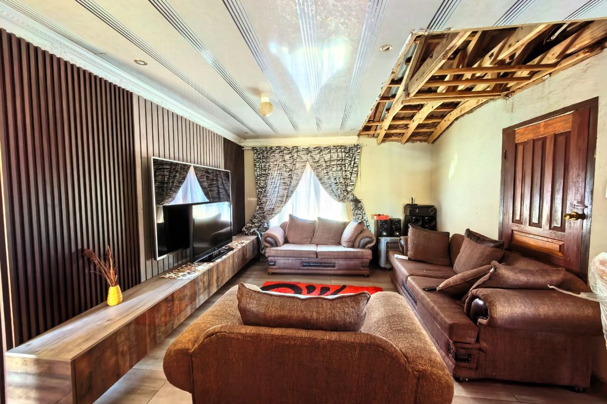 Living room featuring a wood-slat feature wall, built-in media console, and tiled flooring, currently requiring ceiling repairs.