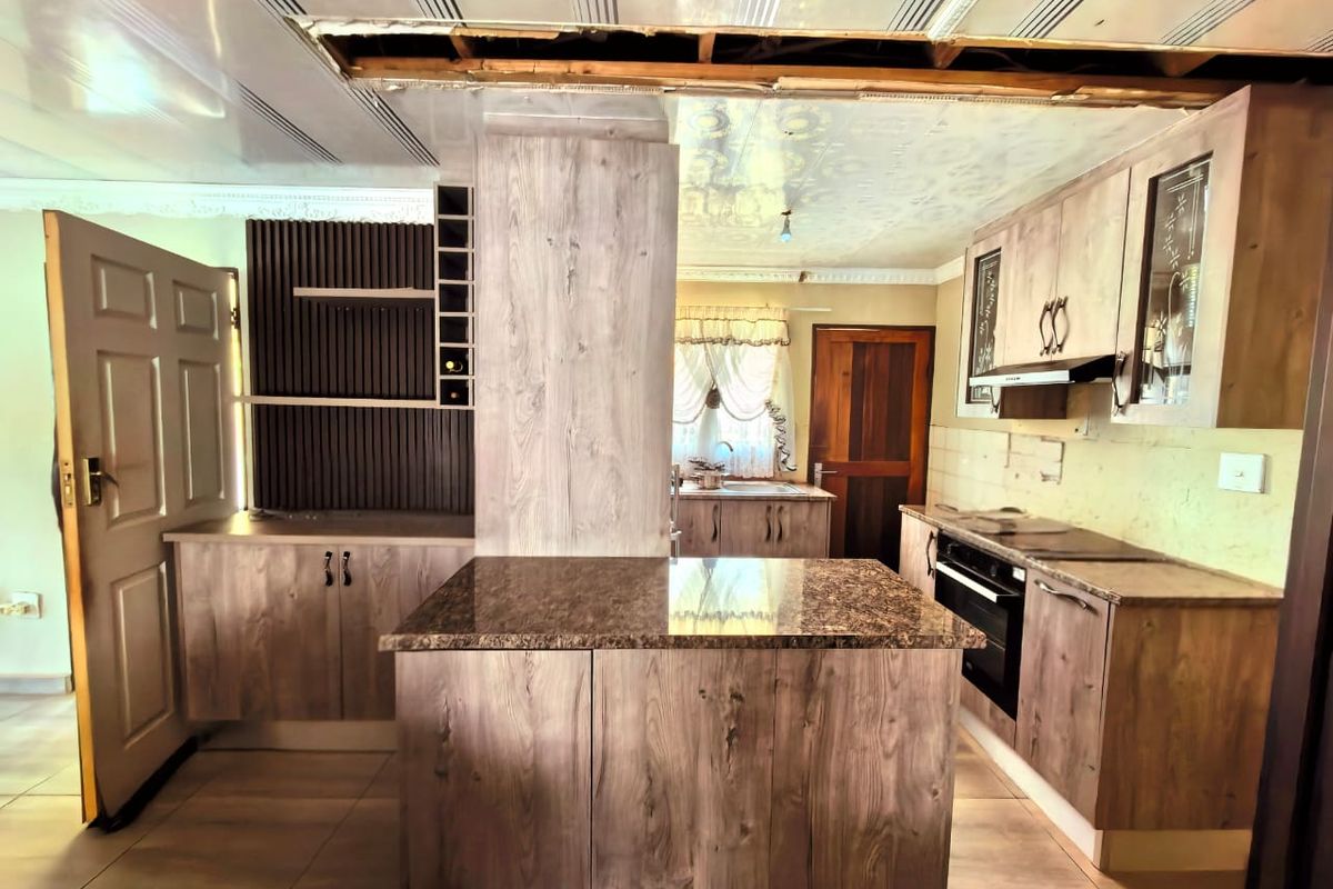 Kitchen featuring wood-look cabinetry, granite countertops, and integrated oven and hob, currently requiring ceiling repairs.