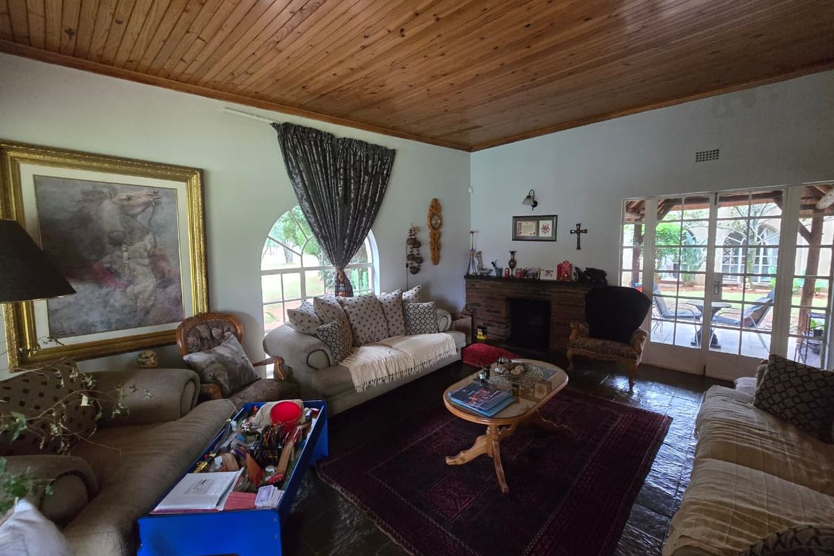 Spacious living room featuring a vaulted timber-clad ceiling, stone flooring, a built-in brick fireplace, and arched windows with access to an outdoor patio.