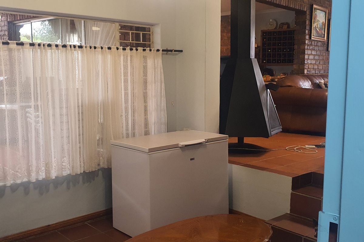 A view from a utility area looking into a living space featuring a built-in fireplace and tiled flooring.