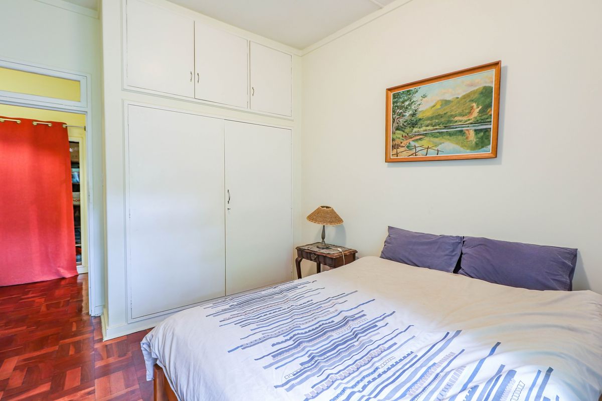 A bedroom featuring built-in floor-to-ceiling cabinetry and traditional parquet wood flooring.