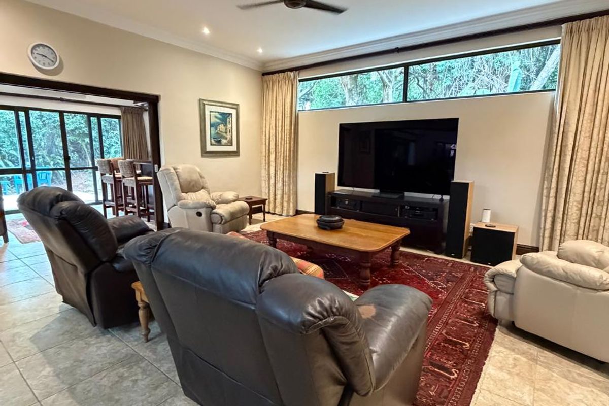 Spacious living room featuring tiled flooring, recessed ceiling lighting, a ceiling fan, and large windows providing natural light and garden views.