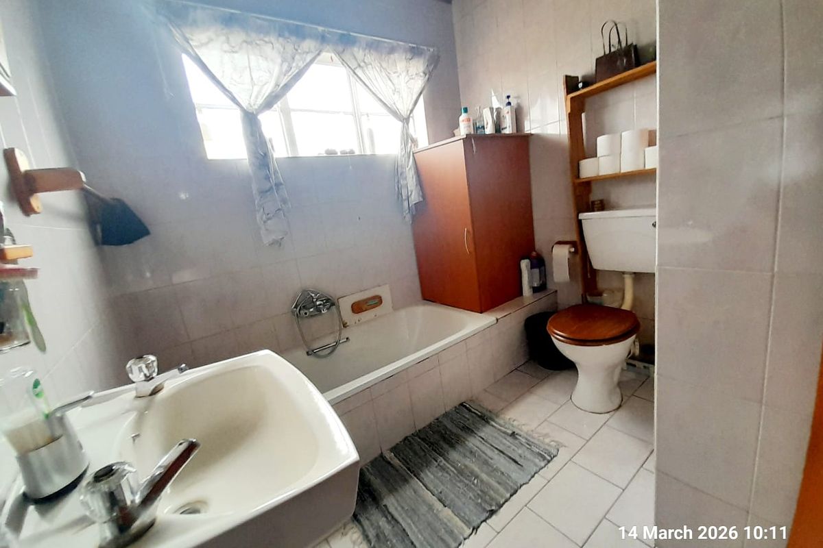 A functional bathroom featuring a bathtub, pedestal sink, and toilet with tiled walls and flooring.