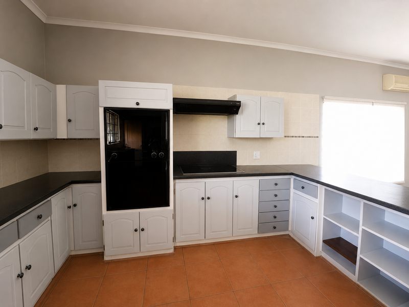 A functional kitchen featuring built-in cabinetry, a dark countertop, integrated oven, hob, extractor fan, and tiled flooring.